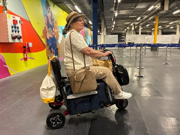 Voyageuse conduisant son scooter pliant ATTO Sport dans un hall d'aéroport
