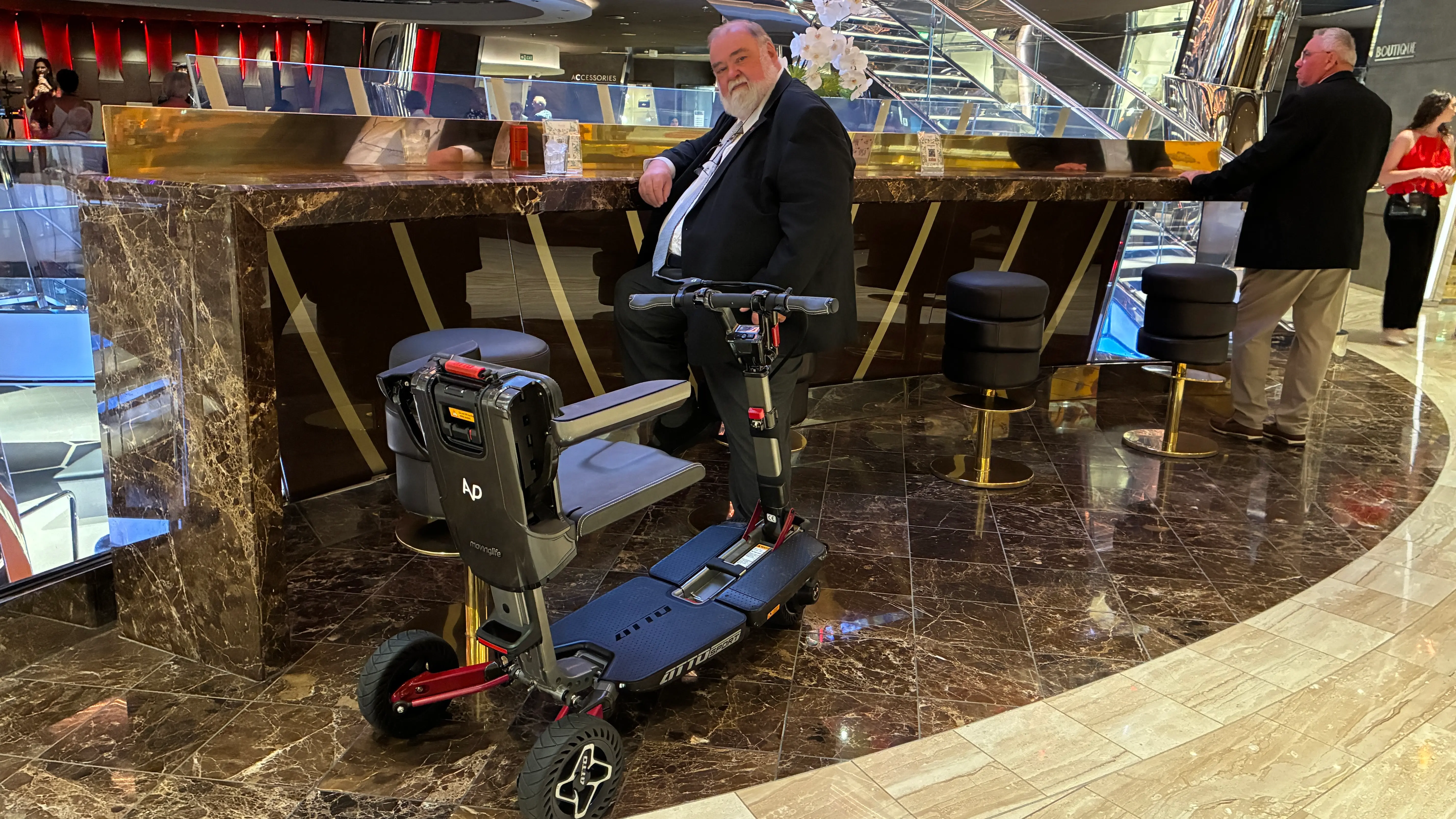 Passager en costume avec son scooter pliant ATTO Sport au bar d'un bateau de croisière