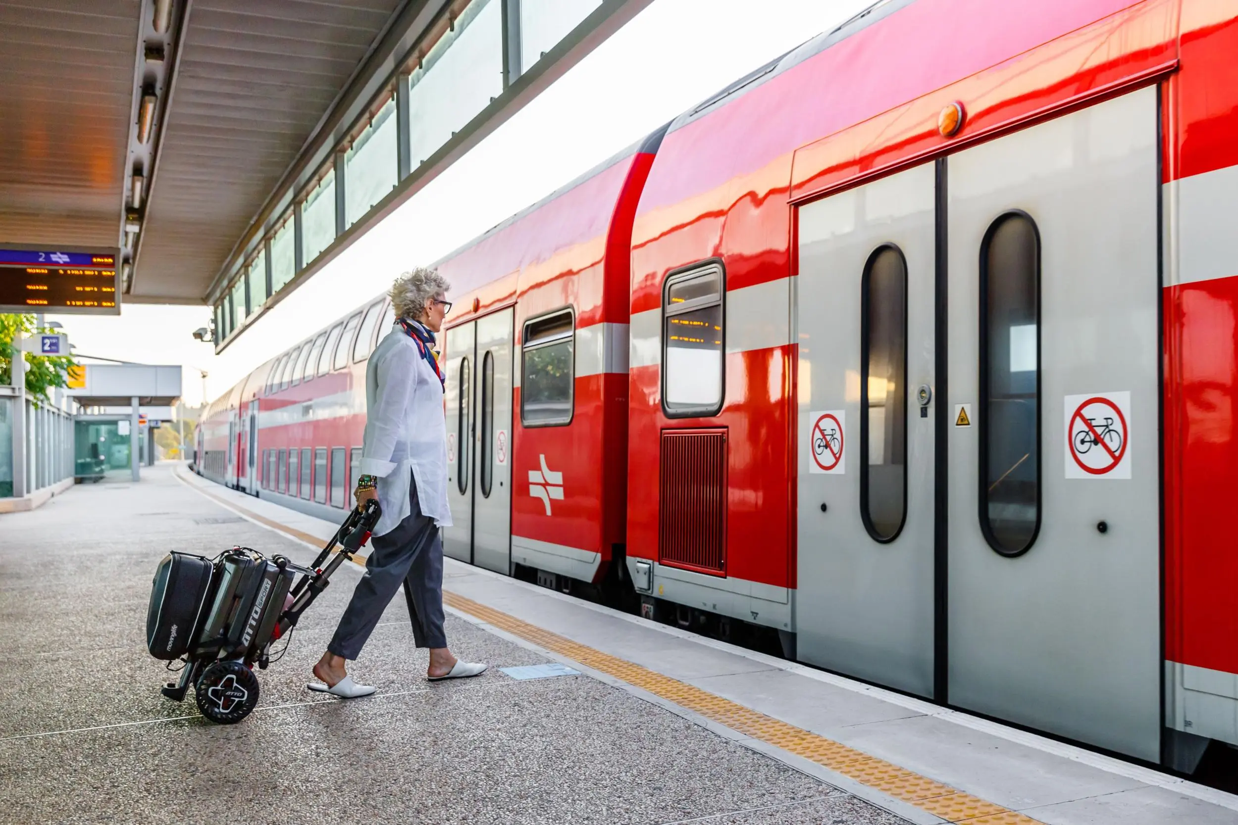 Scooter pliant ATTO Sport tiré comme une valise sur un quai de gare